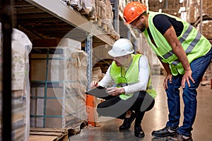 Manager and supervisor taking inventory in warehouse, male workers in uniform talking