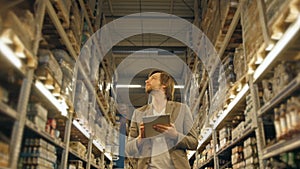 Manager With Tablet PC Checking Goods At Supermarket Warehouse