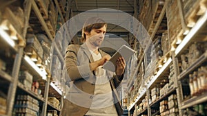 Manager With Tablet PC Checking Goods At Supermarket Warehouse