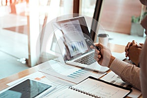 Manager is using a laptop computer while analyzing the company`s financial statements on the screen photo