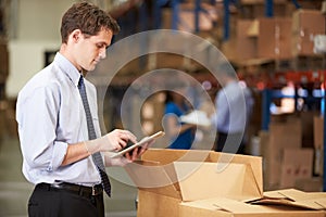 Manager In Warehouse Checking Boxes Using Digital Tablet