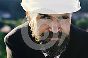 Manager wears smart suit, tie and white hardhat