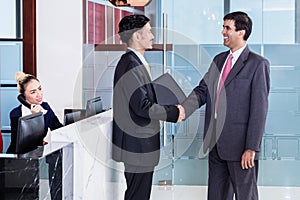 Manager welcoming business associate in office lounge