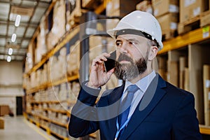 Manager woman in suit calling in a waehouse.