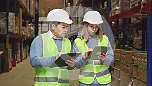 Manager and worker working on tablet and clipboard at stock