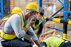 Manager and Workers taking care about their colleague lying on the floor in a warehouse, Warehouse workers man an accident lying
