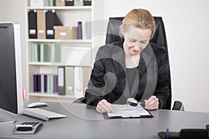 Manageress Reading Documents with Magnifying Glass