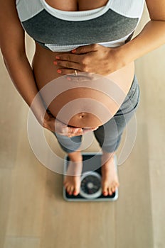 Managing healthy pregnancy weight gain with daily weigh ins. Cropped high angle shot of a pregnant woman weighing