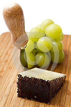 Manchego cheese ang grapes on chopping board photo