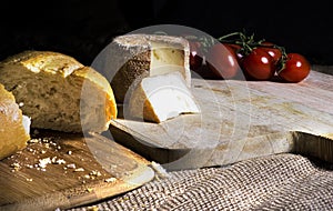 Manchego cheese and tomatoes on rustic table and black background.