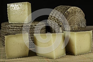Manchego Curado cheeses, one of them cutted into pieces photo
