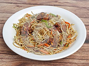 Manchurian Noodles a popular indo-chinese dish served over a rustic wooden background, selective focus