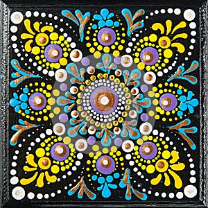 Mandala dot art painting on wood tiles. Beautiful mandala hand painted by colorful dots on black wood. National patterns