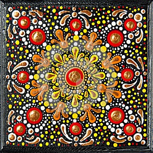 Mandala dot art painting on wood tiles. Beautiful mandala hand painted by colorful dots on black wood. National patterns
