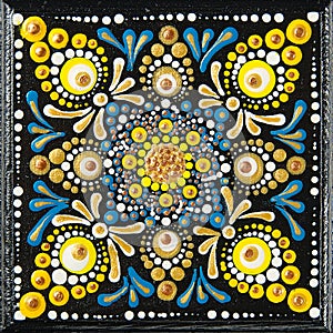 Mandala dot art painting on wood tiles. Beautiful mandala hand painted by colorful dots on black wood. National patterns