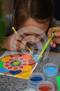 A mandala made of colored sand, the mom with the girls