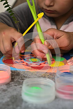 A mandala made of colored sand, the mom with the girls