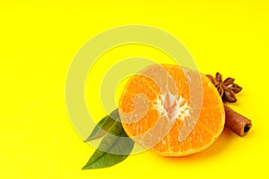 Mandarin with leaves and cinnamon on yellow background