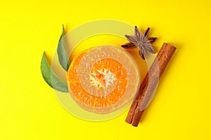 Mandarin with leaves and cinnamon on yellow background