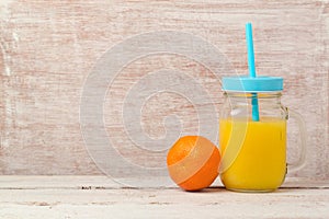 Mandarin orange juice in mason jar and fruit over wooden background with copy space. Healthy eating or dieting