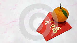 A mandarin orange with red ang pow