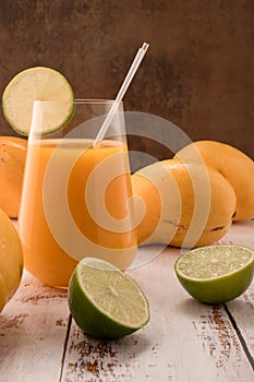 Mandarine drink with lime slice on white vintage wooden desktop with mangos