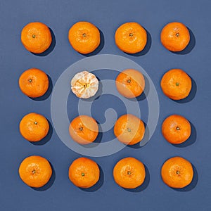 Mandarine or orange pattern on blue background. Tangerine fruit flat lay with one peeled citrus. Summer food creative concept