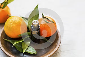 Mandarines essential oil bottle, aromatherapy citrus oil with mandarine fruits in wooden plate