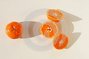 Mandarines, tangerine, clementine slices and shadows top view on white background