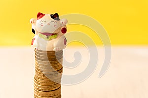 Maneki neko or beckoning cat placed on a coin stack