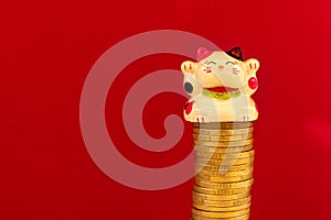 Maneki neko or beckoning cat placed on a coin stack