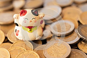 Maneki neko or beckoning cat placed on a coin stack