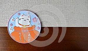 Maneki neko coaster on place mat surface background