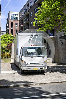 Maneuverable white compact cab over small light duty rig semi truck with long box trailer standing on the urban city street photo