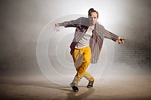 Manful guy with fashionable clothers dancing on foggy weather on the street photo