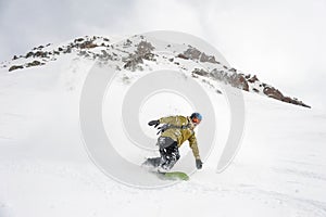 Manful snowboarder moving down the hill in the mountain resort