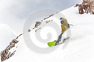 Manful snowboarder riding down the hill in the mountain resort photo