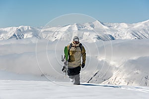 Manful snowboarder walking in the mountain resort