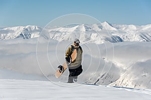 Manful snowboarder walking with the snowboard in the mountain re photo