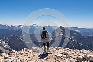 Mangart - Hiker man on top of untamed mountain peak mount Mangart (Mangrt), border Italy Slovenia