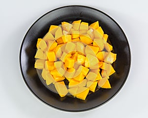 Mango chunks on black plate