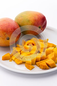 Mango Cubes And Two Whole Mangos On A White Plate