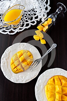 Mango fruit cubes and mango juice puree on dark wooden background.