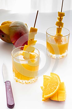 Mango juice with orange. Kitchen knife and chopped fruits