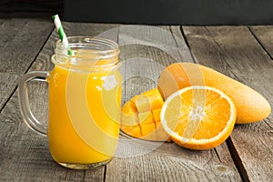 Mango and orange juice and slice of orange on table. Fresh healthy tropical drink.