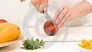 Woman cutting peach. Close up view, white background