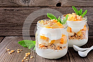 Mango, pineapple parfaits in mason jars on rustic wood