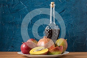 Mango, pomegranate, grapes and a bottle of wine. Still life on a blue background