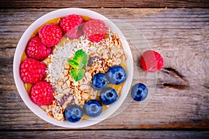 Mango smoothie bowl with raspberries, blueberries, granola and coconut