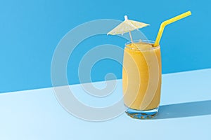 Mango smoothie with a cocktail umbrella. Summer cold drink